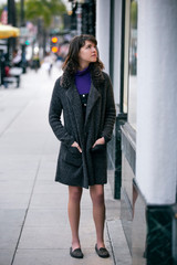 Woman walking outdoors in a city. She is window shopping and looking at a store sale advertising or...