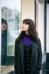 Woman walking outdoors in a city. She is window shopping and looking at a store sale advertising or...