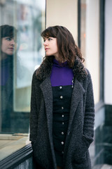 Woman walking outdoors in a city. She is window shopping and looking at a store sale advertising or...