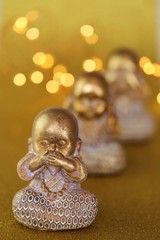 monk figurine.I do not see, I do not hear, I do not speak concept.golden monk figurine set on golden background with blurred golden bokeh.The religion and the motto of life.Statues with emotions