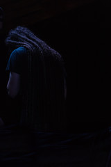 Hombre rasta espaldas en fondo negro orando cantando camisa azul oscura