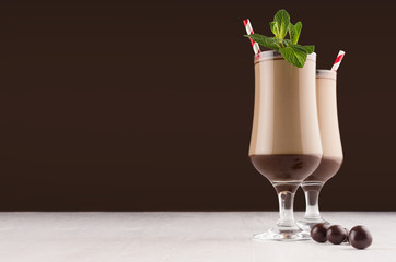 Christmas beverage - irish coffee with fresh green mint, red straw and chocolate candies in elegant dark brown interior, copy space.