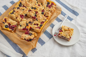 crumble cake in a baking form and pieces of the cake on a table
