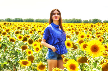 Fototapeta premium Young happy girl on a walk in a field with sunflowers