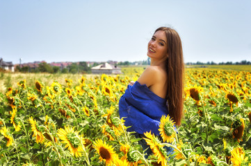 Young happy girl on a walk in a field with sunflowers