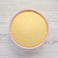 Top view, dry semolina durum flour in a pink bowl over white wooden surface. Overhead, from above, flat lay.