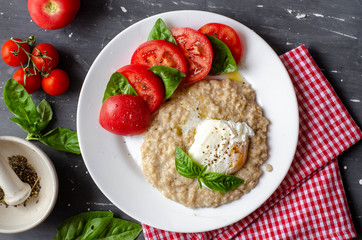 oatmeal with poached egg, tomatoes and basil. fresh tasty proper nutrition meal. healthy food for breakfast