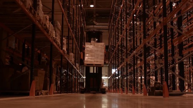 Work of the loader in the logistics warehouse. Storage of cargo on the racks. Electric stacker raises the load on the pallet to height.