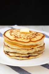 Homemade pancakes with butter on a white plate, side view. Close-up.