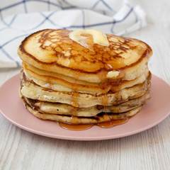Homemade pancakes with butter and maple syrup on a pink plate, low angle view. Close-up.