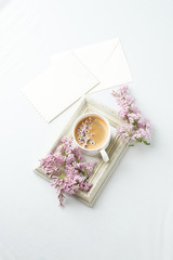 Fototapeta na wymiar Modern still life with lilac flowers, frame and cup of coffee, on white wbackground, copy space. Holiday or wedding background. minimalist style, female breakfast