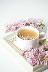 Obraz na płótnie Canvas Modern still life with lilac flowers, frame and cup of coffee, on white wbackground, copy space. Holiday or wedding background. minimalist style, female breakfast