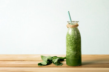 the Healthy fresh  green smoothie juice in the glass bottle on wooden table for healthy detox and diet  habits concept