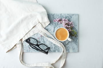 Woman desktop elegant. Coffee cup and ililac branches on marble plate on white the table. Mock-up for artwork. View from above. Flat lay. Springtime famale concept