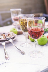 Glasses of white and rose wine, grilled fish plates, vegetables, salad and fruits on the table. Summer party in the backyard. Vertical shot