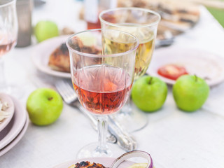 Grilled grouper, glasses with white and rose wine, plates, vegetables, salad and fruits on the table. Summer party in the backyard. Horizontal shot