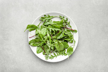 Fresh salad with green leaves on plate, top view