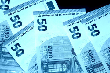 Fifty euro notes on a dark background close up. Blue color toned