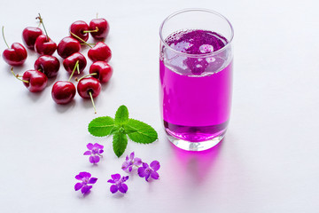 Cherry juice, cherry on a sunny table. Summer drinks. Juice in glass, cherry juice