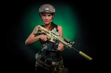 Fototapeta premium the girl in military special clothes posing with a gun in his hands on a dark background in the haze