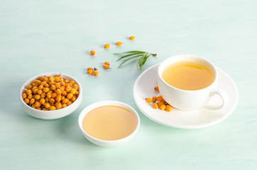 Sea buckthorn in porcelain bowl, honey and cup of  tea with Sea buckthorn on blue table. top view