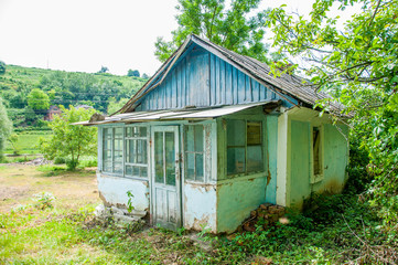 Old wooden house near the forest and lawn. Summer