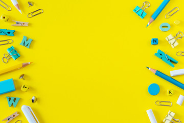 Multicolored school supplies on yellow background with copy space.