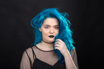 Style and fashion concept - Young and attractive woman with blue hair posing over black background
