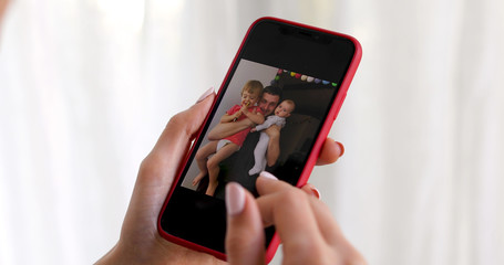 Woman hand with smartphone showing kid picture on white background