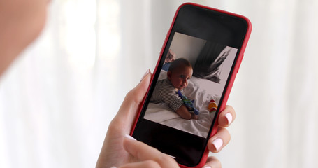 Woman hand with smartphone showing kid picture on white background
