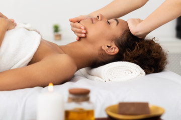 Obraz na płótnie Canvas Afro Woman Enjoying Face Massage, Relaxing In Spa Salon