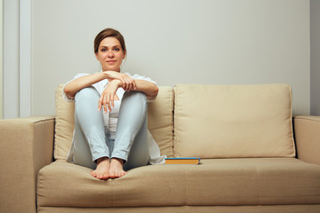 Smiling woman sitting on sofa with his legs.
