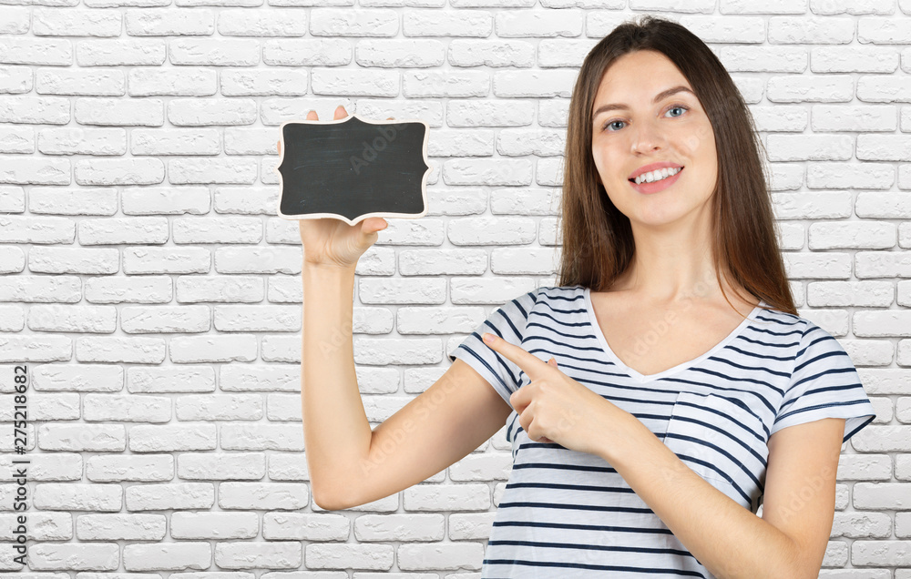 Canvas Prints Photo of happy young woman standing, looking at camera showing copyspace pointing