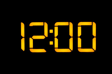 Electronic digital clock with yellow numbers on a black background shows the time Twelve zero zero...