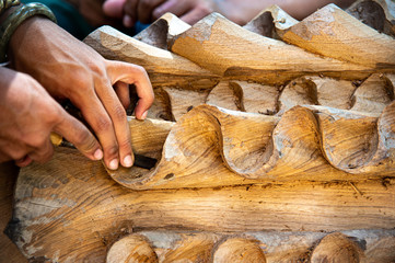 Closeup hands of professional local craftman carve teak timber with gouge tool create beautiful...
