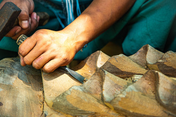 Closeup hands of local craftman carpenter carve teak timber with gouge tool create delicate handcraft art in Northern Thailand.