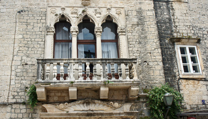 Stone house with windows and balcony in the street of old town, beautiful architecture, sunny day, Trogir, Dalmatia, Croatia