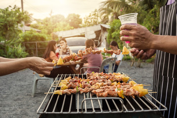 BBQ party group of people at barbecue dinner friends having food together outdoor as summer with friendship asian person.