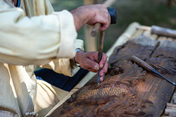 Closeup hands of local craftman carve with gouge tool and create anamazing Thai Northern handcraft art in Thailand.