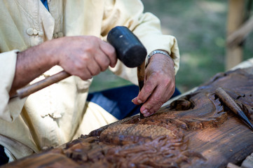 Closeup hands of local Thai craftsman carve with chisel and gouge tool on wood creating Thai Northern handcraft art, carpenter 