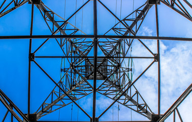 Support for power transmission lines, against the background of the blue sky, bottom-up view.