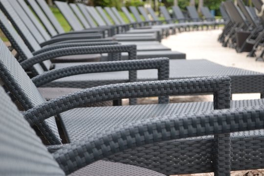 Line of empty unoccupied grey wicker sun loungers or sunbeds for suntanningon a beach in Australia