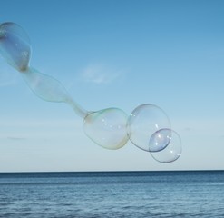 Large, soap bubbles against the blue sky. Lake Ladoga, sunny day.