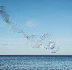 Large, soap bubbles against the blue sky. Lake Ladoga, sunny day.