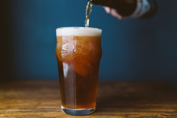 Pouring beer into glass. Dark background