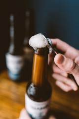 Hand opening a bottle of beer