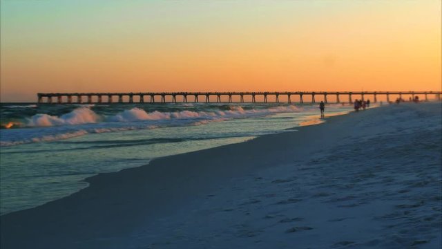 Locals and tourists walk the beach as the day comes to an end in this small beach town time lapse
