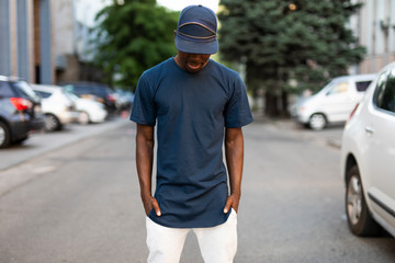 African american unrecognizable man in empty t-shirt and cap standing in city