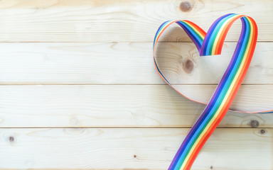 LGBT, LGBTQ for gay pride month and International Day Against Homophobia, Transphobia and Biphobia with rainbow ribbon flag awareness in heart shape on white wood background
