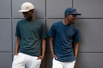 African men models posing in t-shirts leaning on building wall